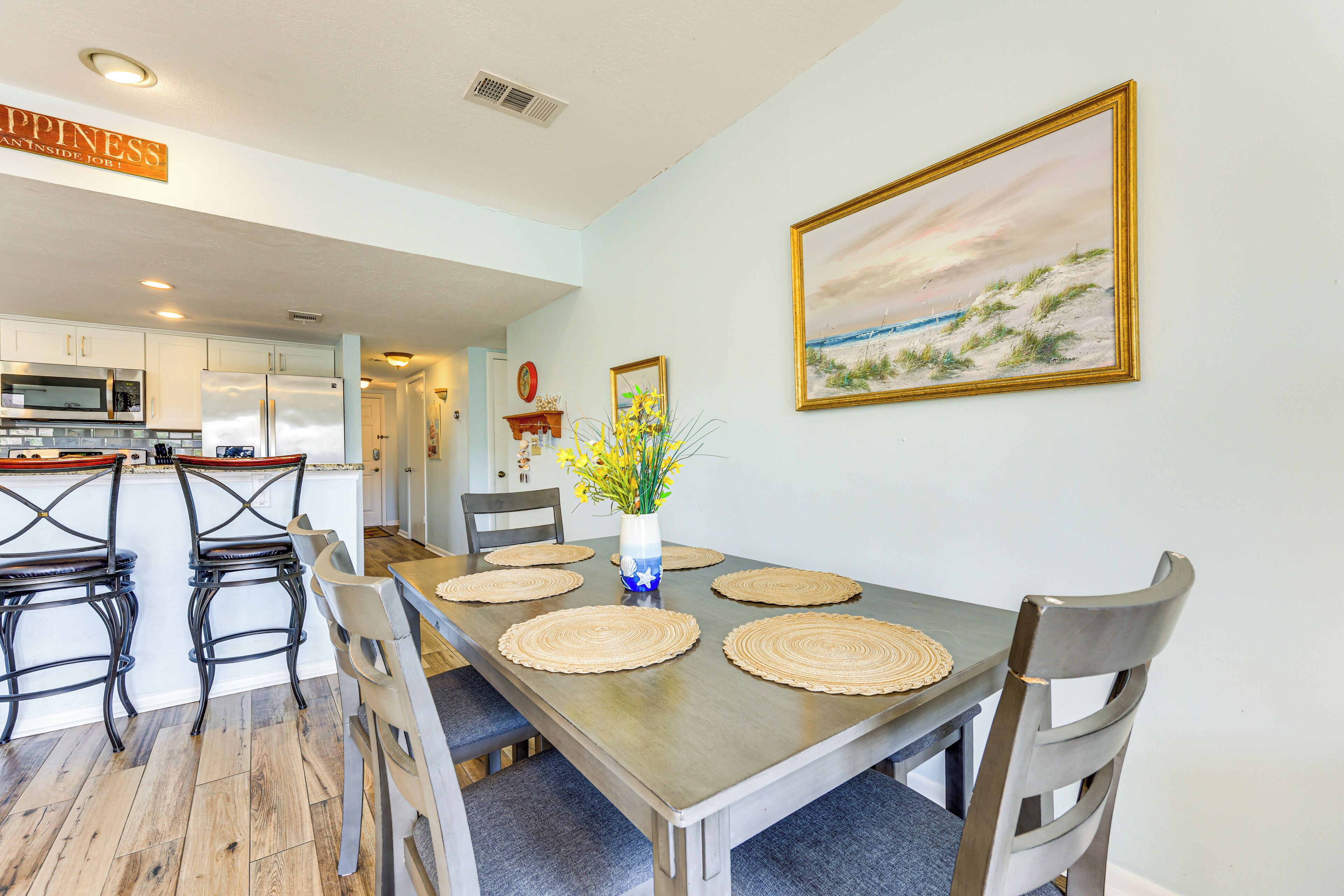 A dining area with a long table, chairs, and a vase with flowers.