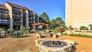 Une cour avec un foyer en pierre, des sièges d’extérieur et une pergola.