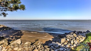 Une plage bordée d’une côte rocheuse, sous un ciel bleu et dégagé.