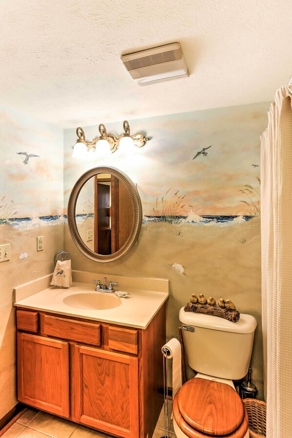 A bathroom with a wooden vanity, a round mirror, and a toilet. - Waterfront Port Clinton Condo w/ Pool Access! (Port Clinton)