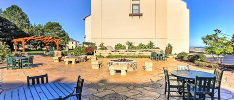 Un edificio con fachada color beige, un patio de piedra con asientos exteriores y una chimenea.