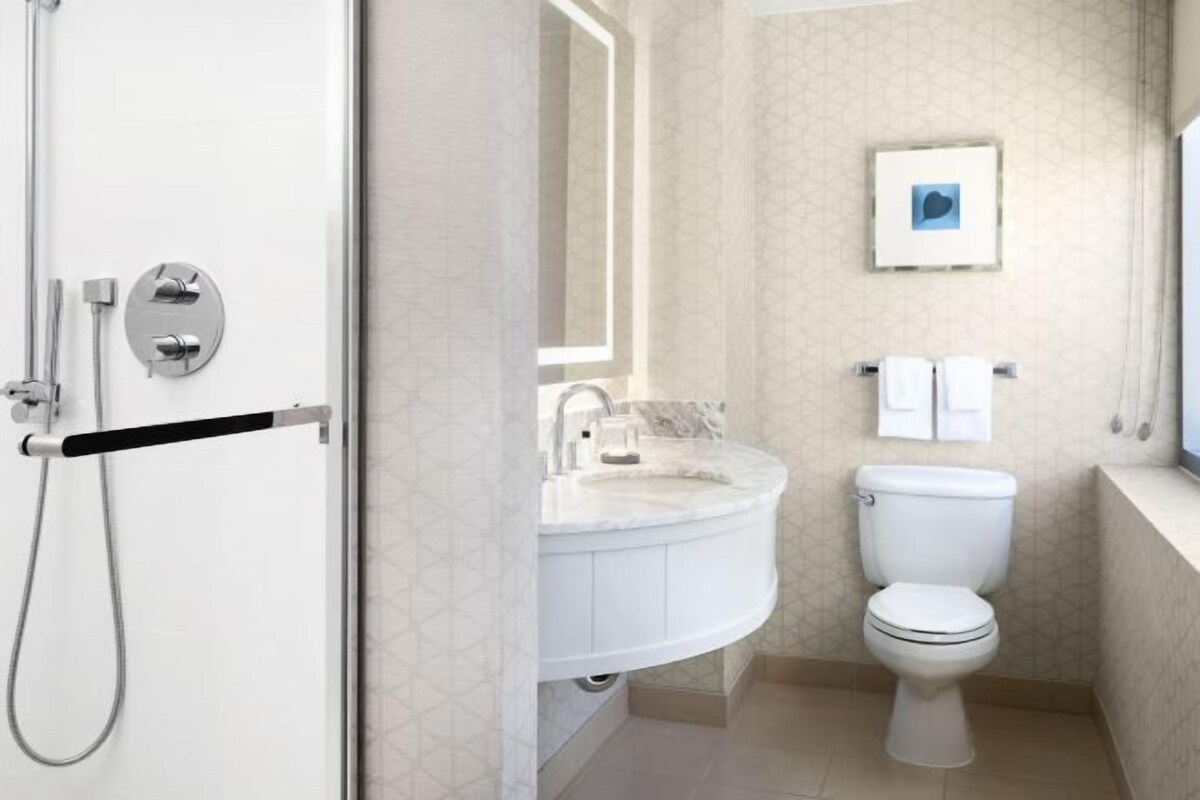 A modern bathroom with a shower, toilet, and sink.