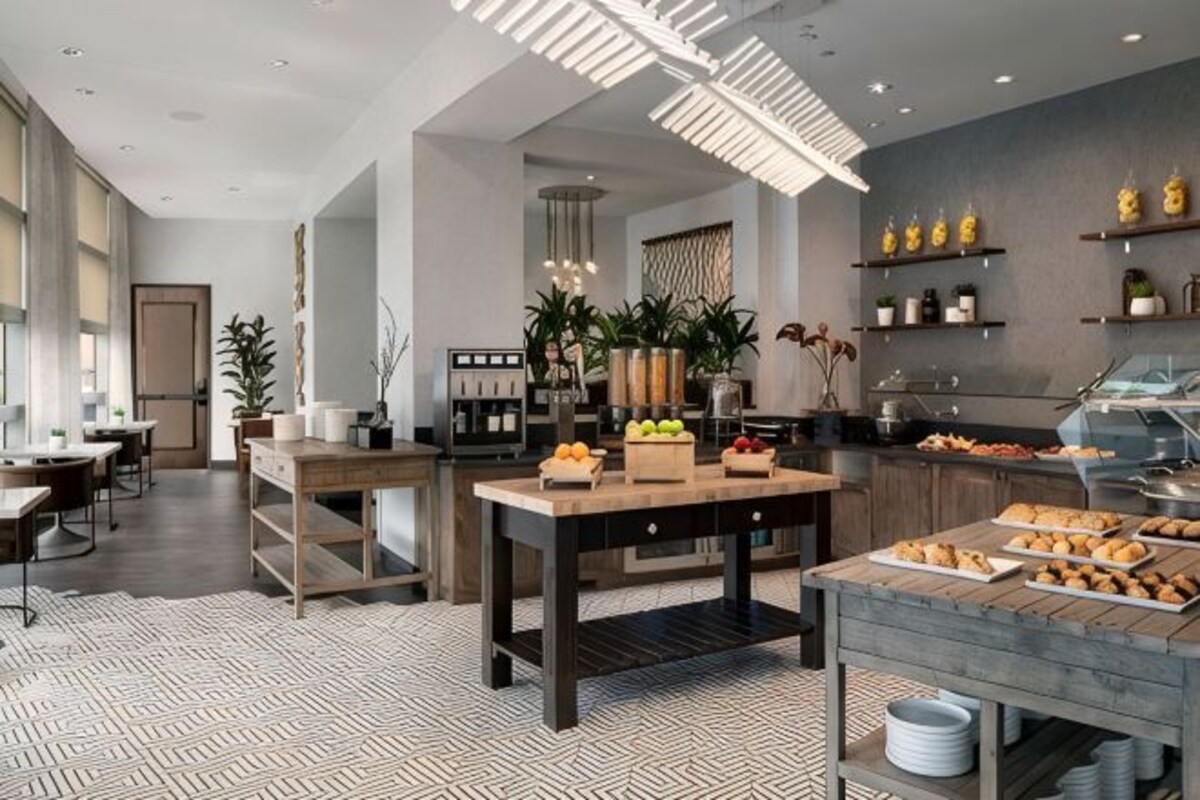 A modern kitchen with a central island, built-in appliances, and a variety of food items displayed.