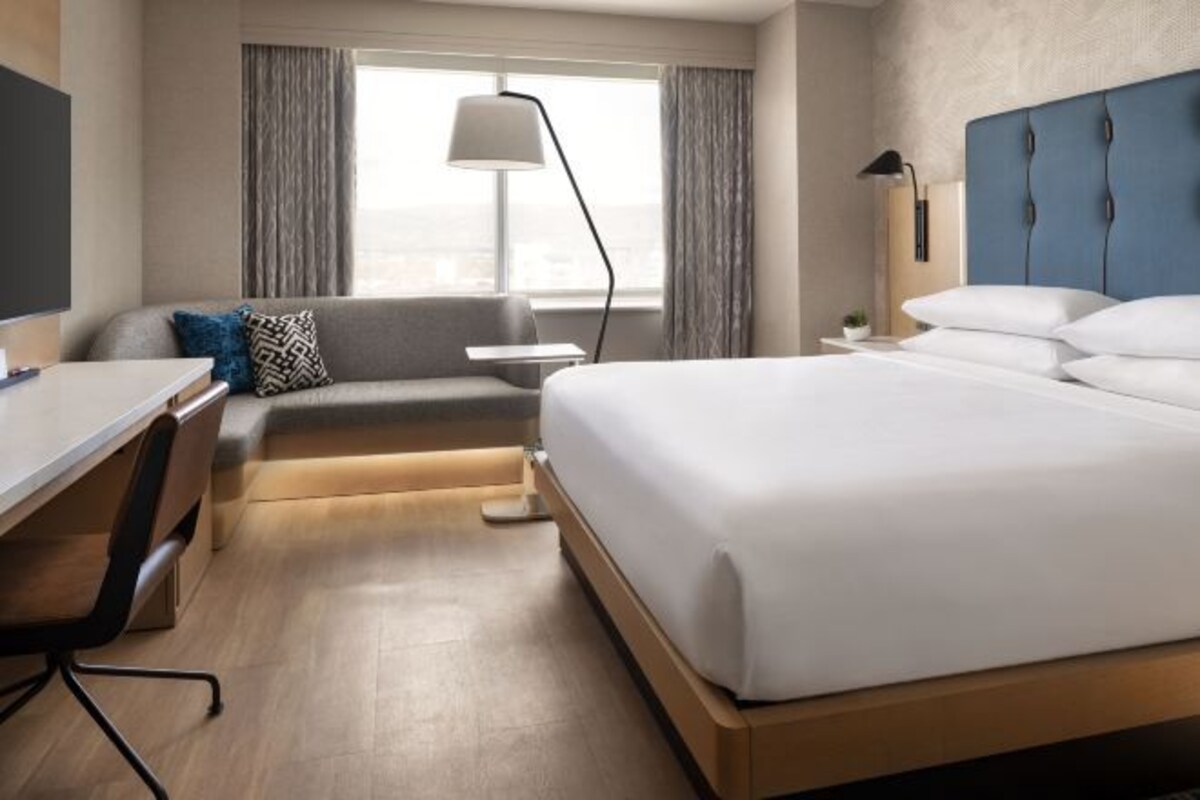 Een moderne hotelkamer met een groot bed, een bureau en een bank.