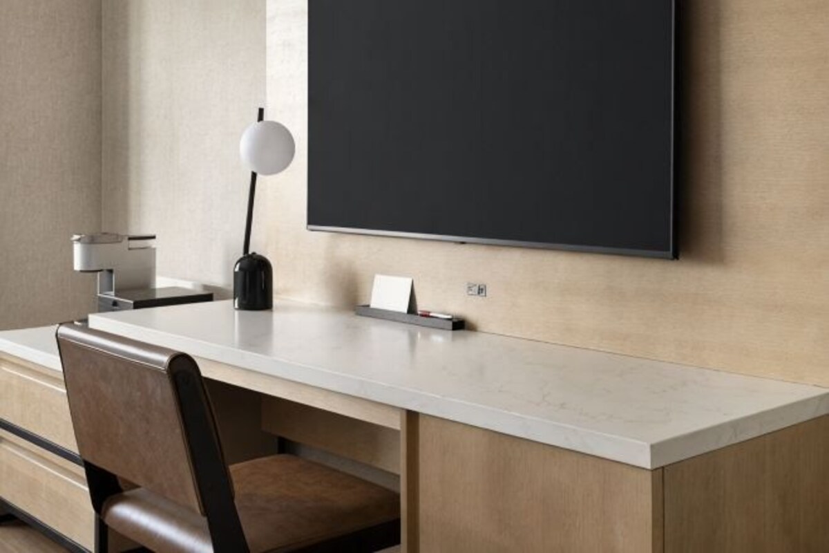 Een moderne kamer met een bureau, stoel en een grote flatscreen televisie aan de muur.