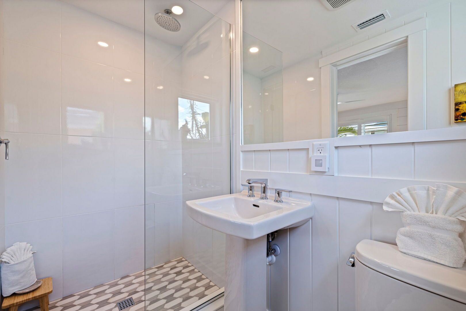 A modern bathroom with a glass shower enclosure, a white sink, and a toilet.