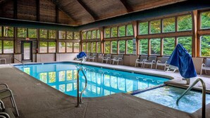 An indoor swimming pool with clear views of the surrounding forest through large windows. - Indoor Pool & Golf Course Views: Lake Lure Condo! (Lake Lure)