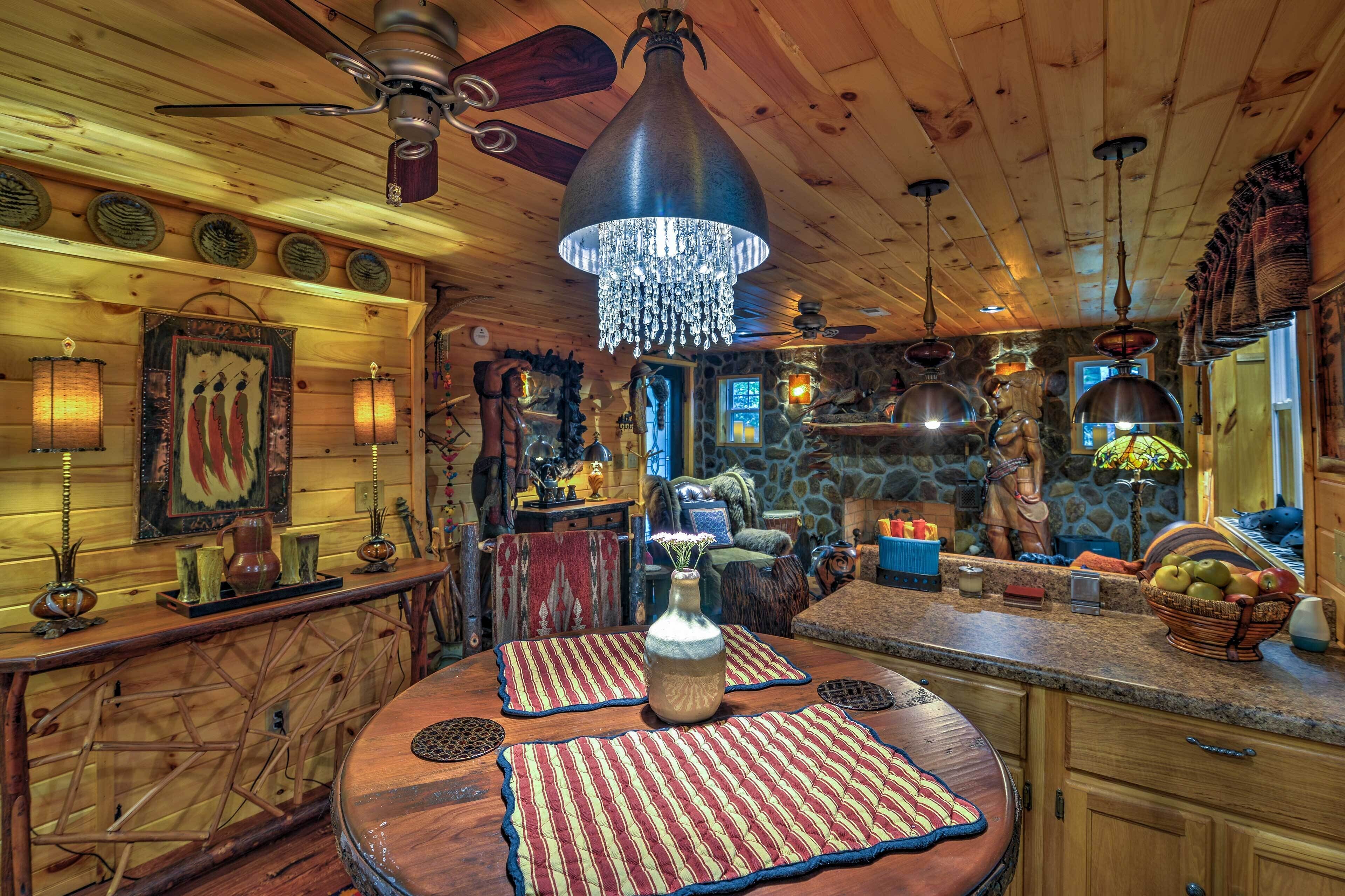 A rustic interior with a wooden ceiling, a chandelier, and a stone wall.