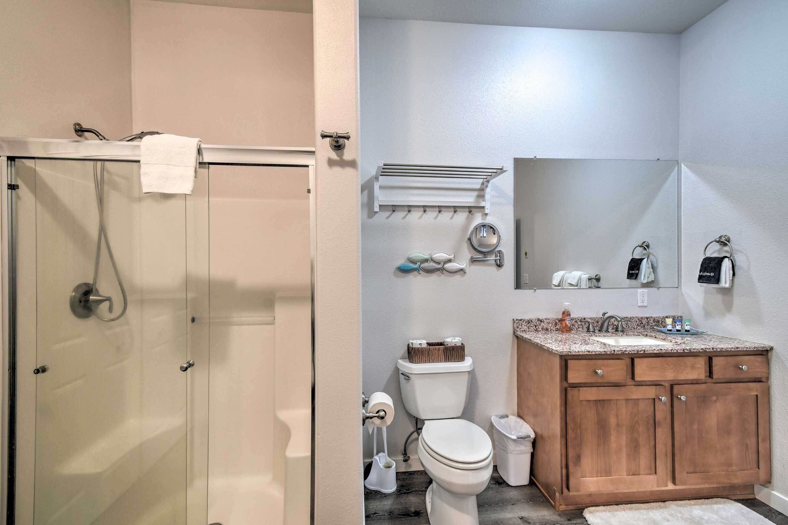 A bathroom with a glass shower enclosure, a toilet, a sink with a vanity, and a mirror above the sink.