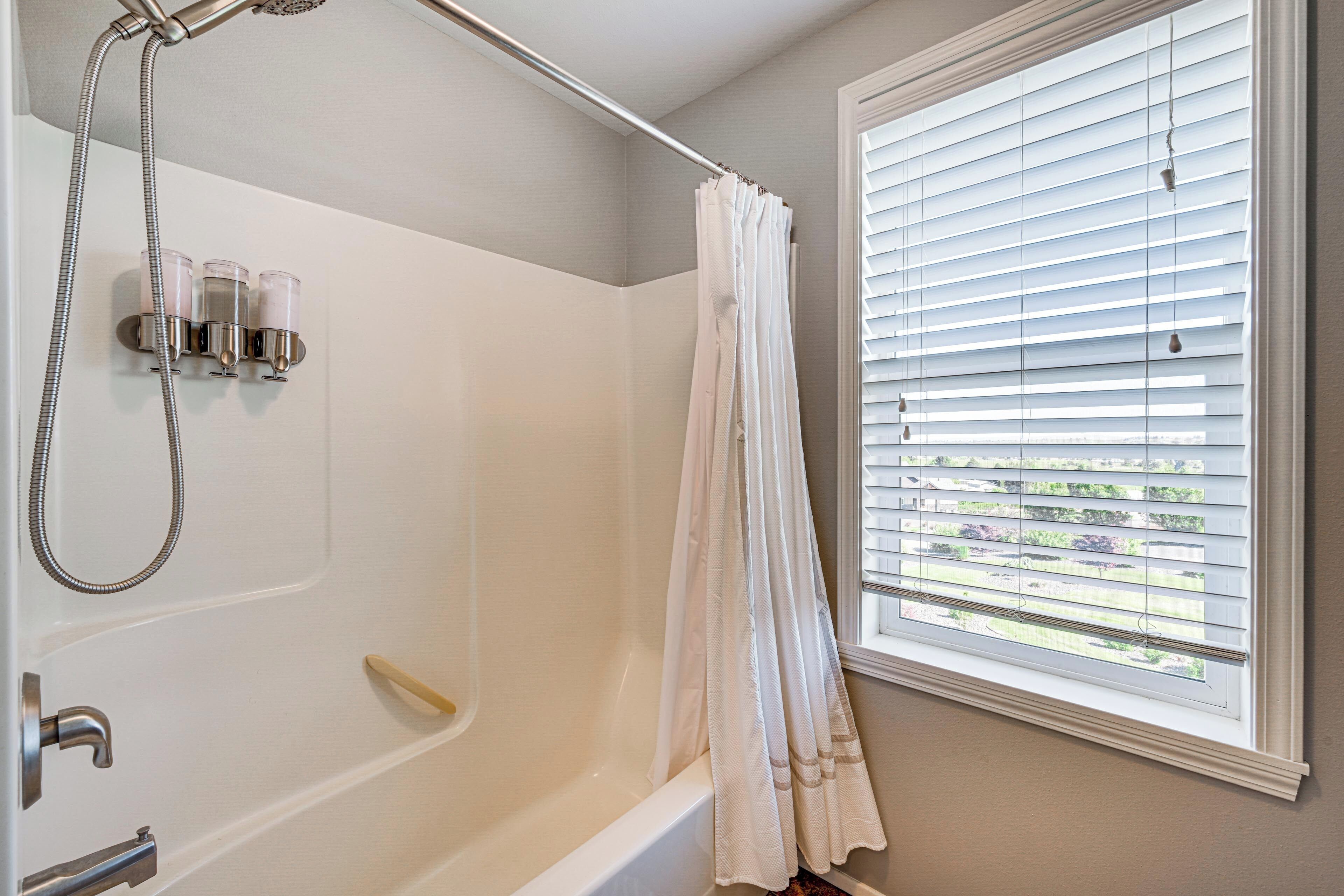 Ein Badezimmer mit Badewanne, Dusche und Fenster mit Jalousien.