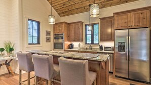 A modern kitchen with wooden cabinets, stainless steel appliances, and a central island with bar stools. - Hike, Fish & Golf! Serene Mtn Retreat in Glenville (Glenville)