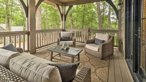 A covered porch with wicker furniture, a glass coffee table, and a view of a wooded area. - Hike, Fish & Golf! Serene Mtn Retreat in Glenville (Glenville)