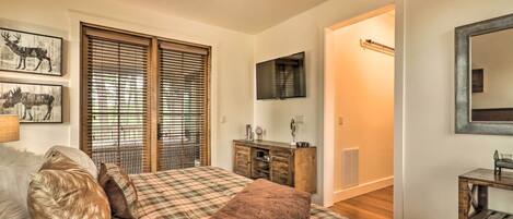 A bedroom with a bed, a ceiling fan, a dresser, a mirror, and a television.