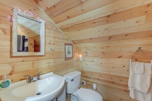A wooden cabin bathroom with a sink, toilet, and mirror. - Unique Converted Trailer in Marshall: Pet Friendly (Marshall)
