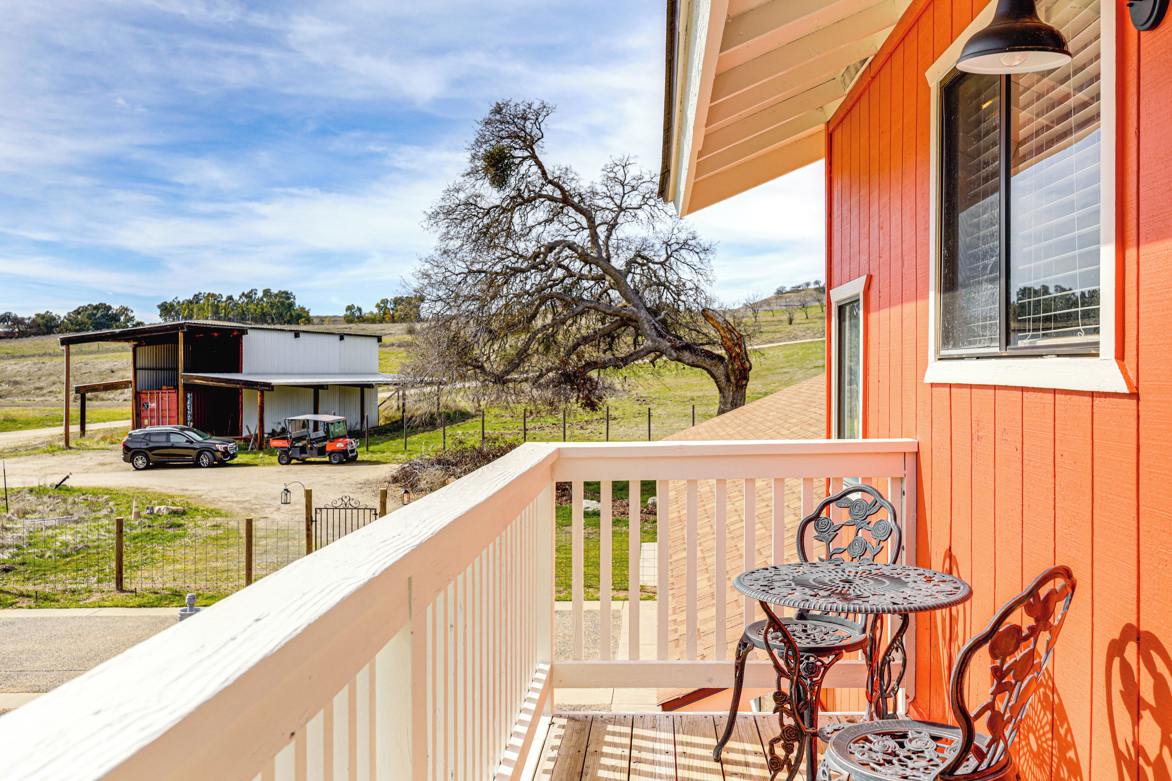 A wooden deck with a metal table and chairs, a building with orange siding, and a clear sky.