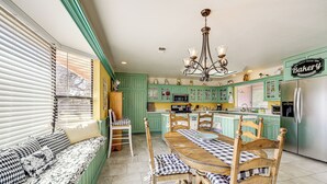 A kitchen with green cabinets, a wooden dining table, and a bench with checkered cushions. - Pleasant Valley Wine Trail Home - Near Paso Robles (San Miguel)