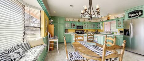 A kitchen with green cabinets, a wooden dining table, and a bench with checkered cushions.