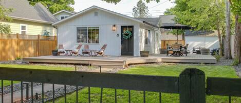 A house with a deck, outdoor furniture, and a fenced yard.