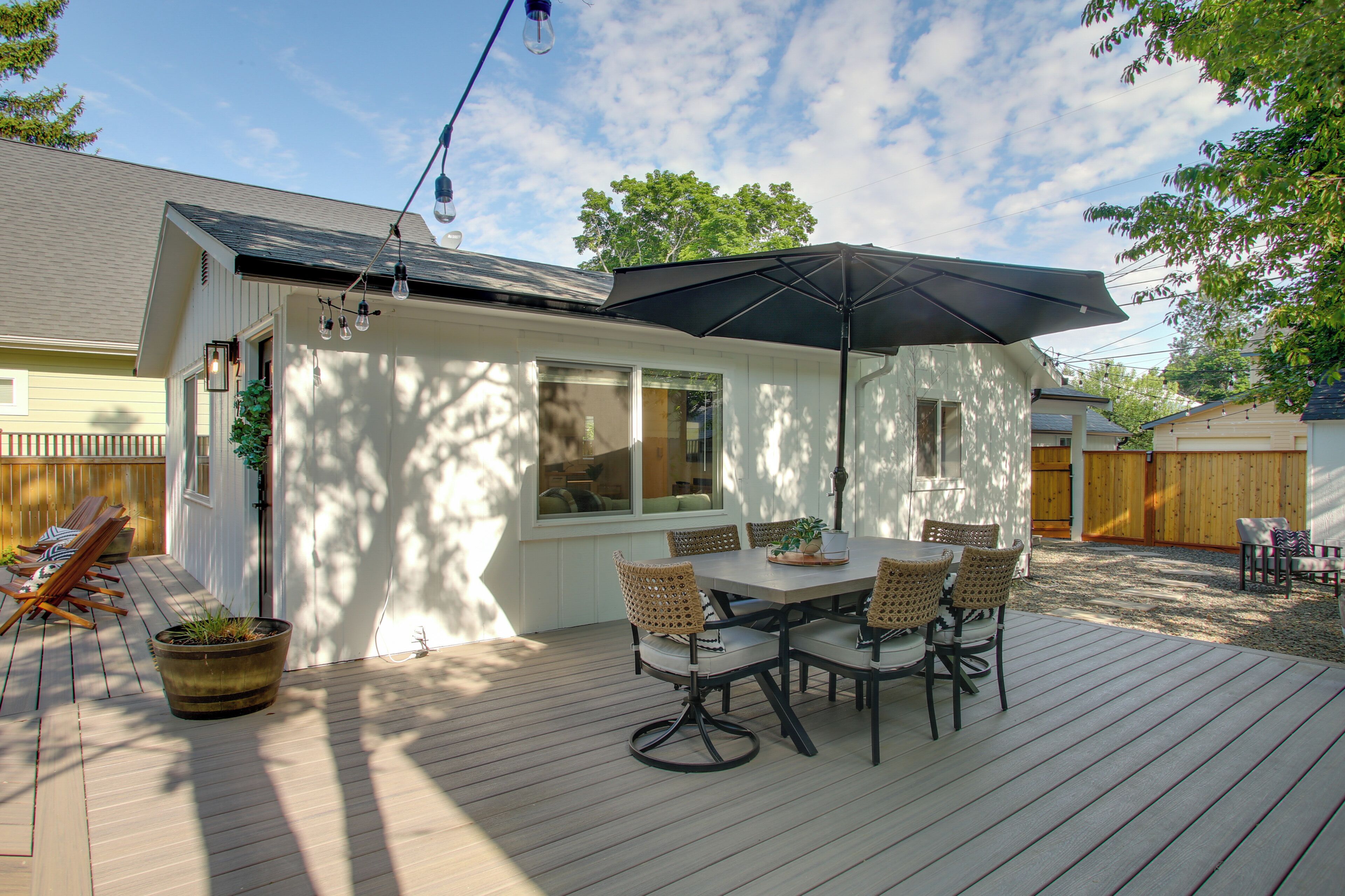 Eine überdachte Terrasse mit Tisch, Stühlen, einer Topfpflanze und einer Pendelleuchte.