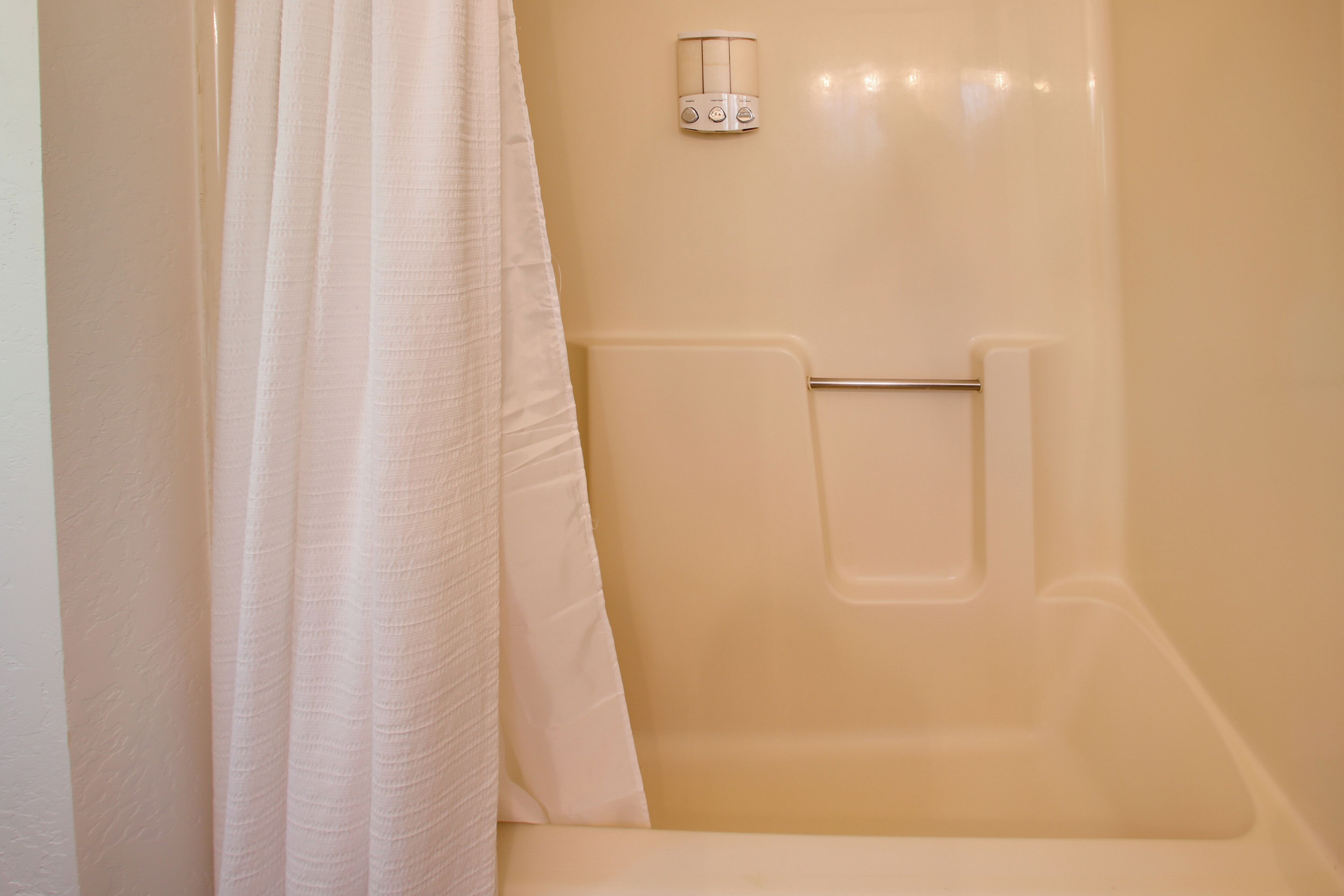 A bathroom with a bathtub, a towel rack, and a shower curtain.