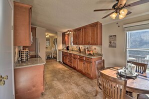 A kitchen with wooden cabinets, a dining table with chairs, and a ceiling fan. - White River Fishing Escape w/ Deck & Patio! (Cotter)