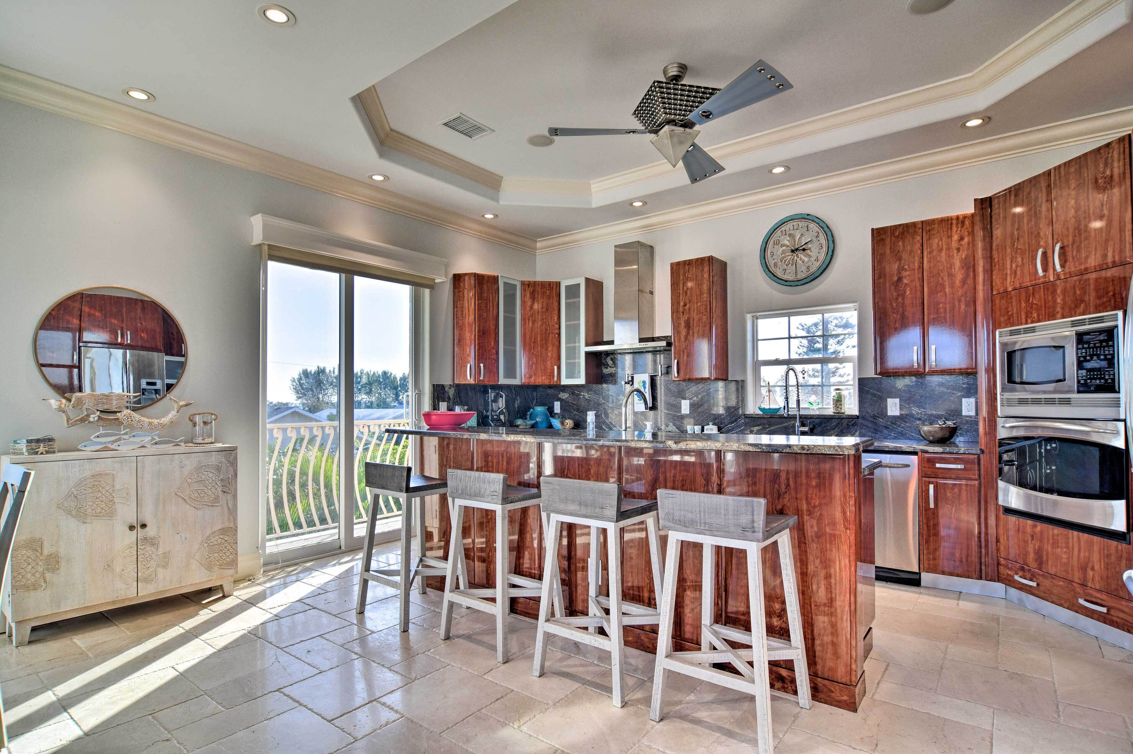 A modern kitchen with a central island, bar stools, and a ceiling fan.