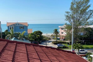 A coastal residential area with a clear view of the beach, houses with red roofs, and a stop sign visible. - Bradenton Townhome - Walk to Locals-only Beach! (Bradenton Beach)