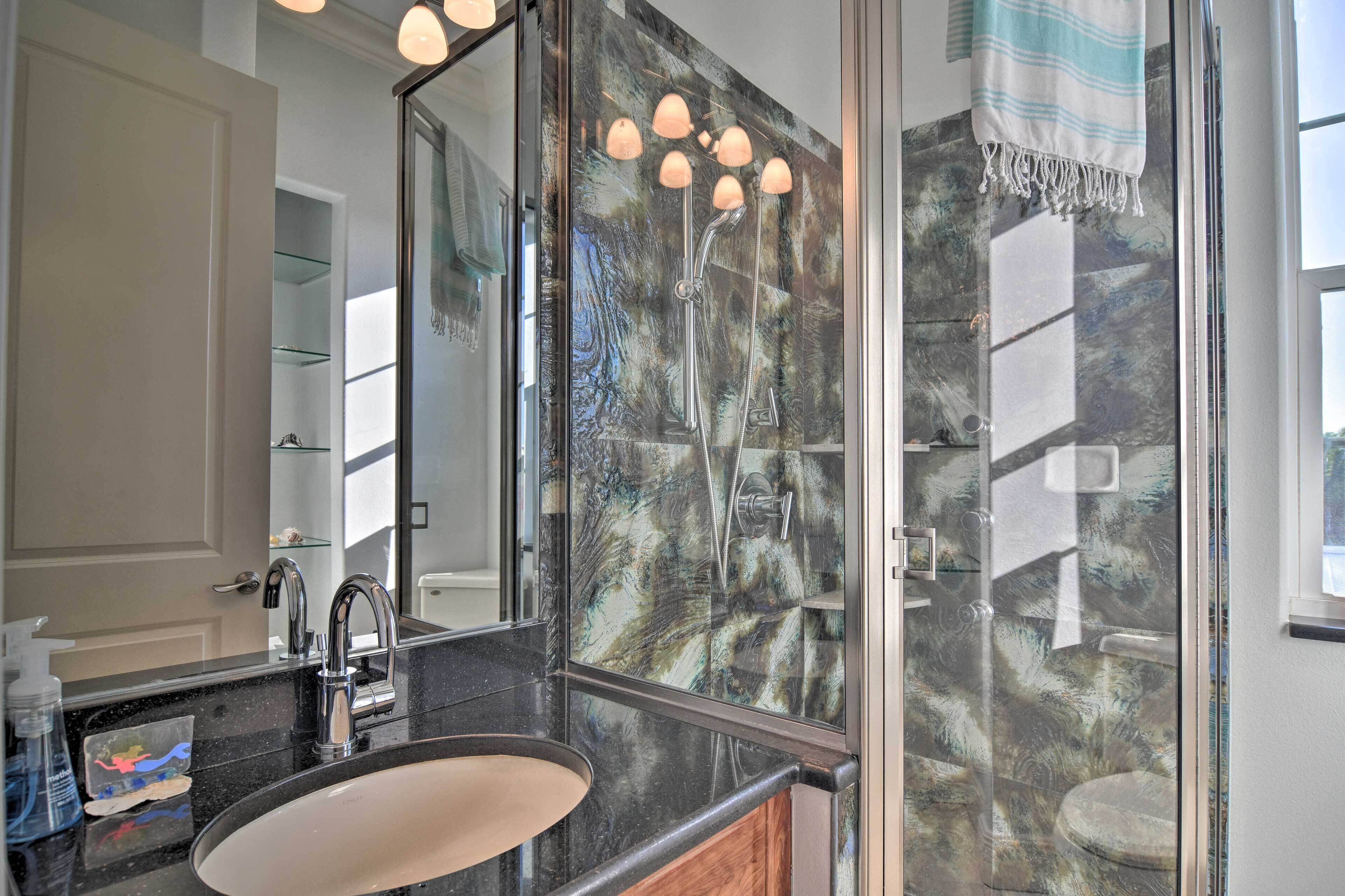 A bathroom with a large mirror, a sink, and a glass shower enclosure.