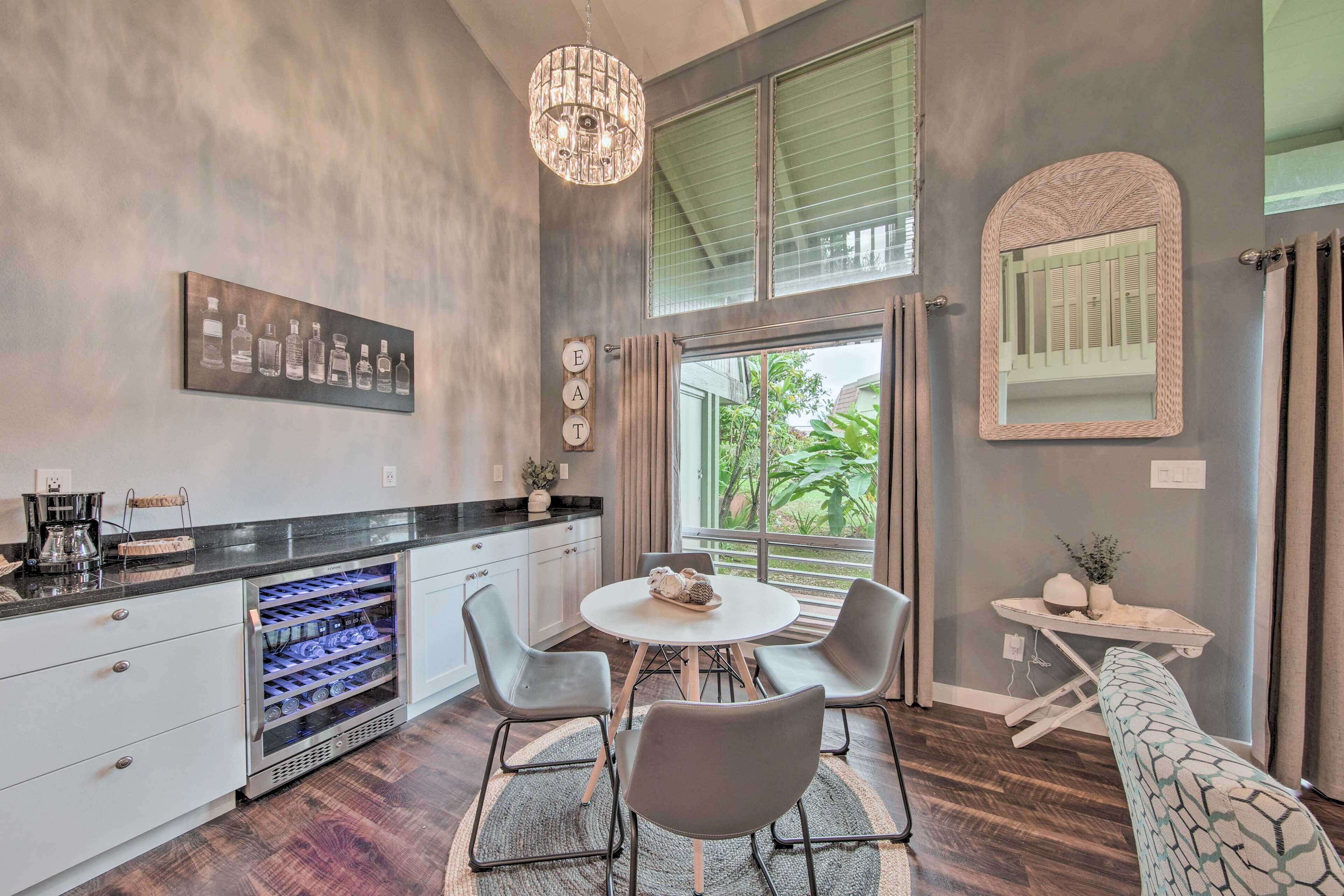 A modern kitchen with a wine cooler, a dining table with chairs, and a large window with curtains.