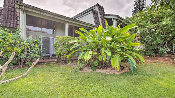A house with a large window, a chimney, and a garden with various plants. - Coastal Escape Condo w/ Pool, Near Beaches! (Princeville)