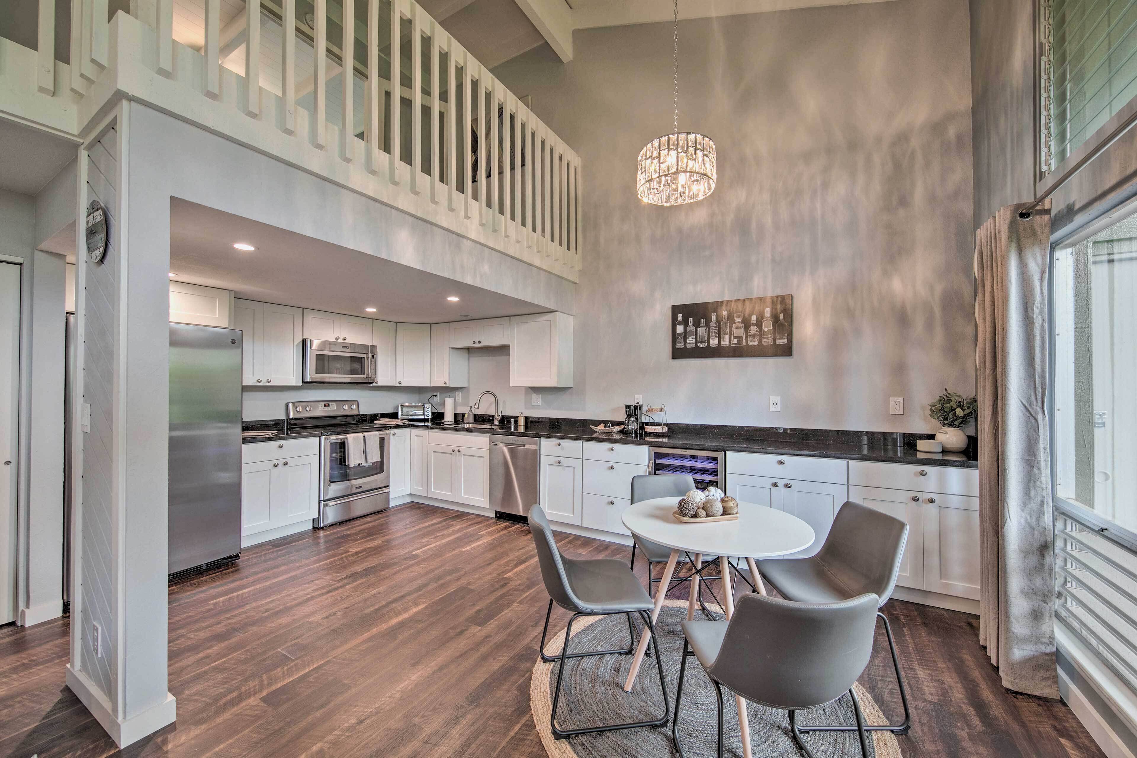 A modern kitchen with a dining area, featuring a chandelier, stainless steel appliances, and a view of the outdoors.