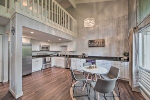 Una cucina moderna con zona pranzo, con un lampadario, elettrodomestici in acciaio inossidabile e vista sull'esterno.