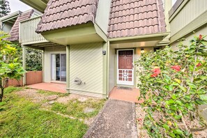 A two-story house with a green exterior, a brown door, and a small porch area.