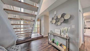 A modern interior with a wooden staircase, a console table with decorative items, and a wall with circular patterns.