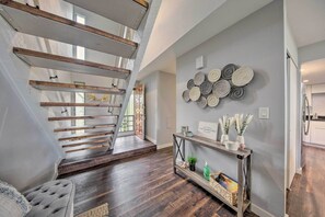 A modern interior with a wooden staircase, a console table with decorative items, and a wall with circular patterns.