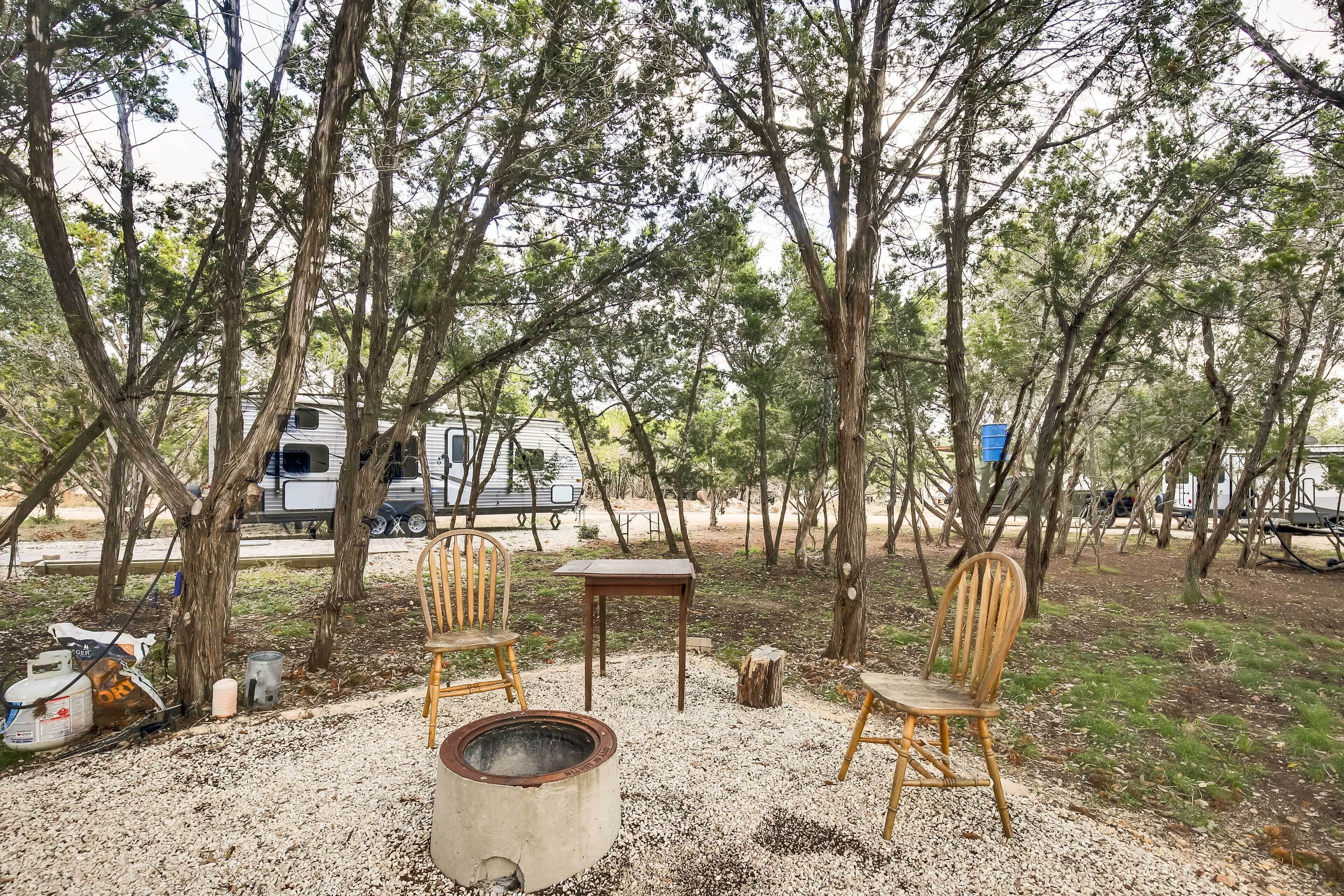 A campsite with a fire pit, wooden chairs, and a table.