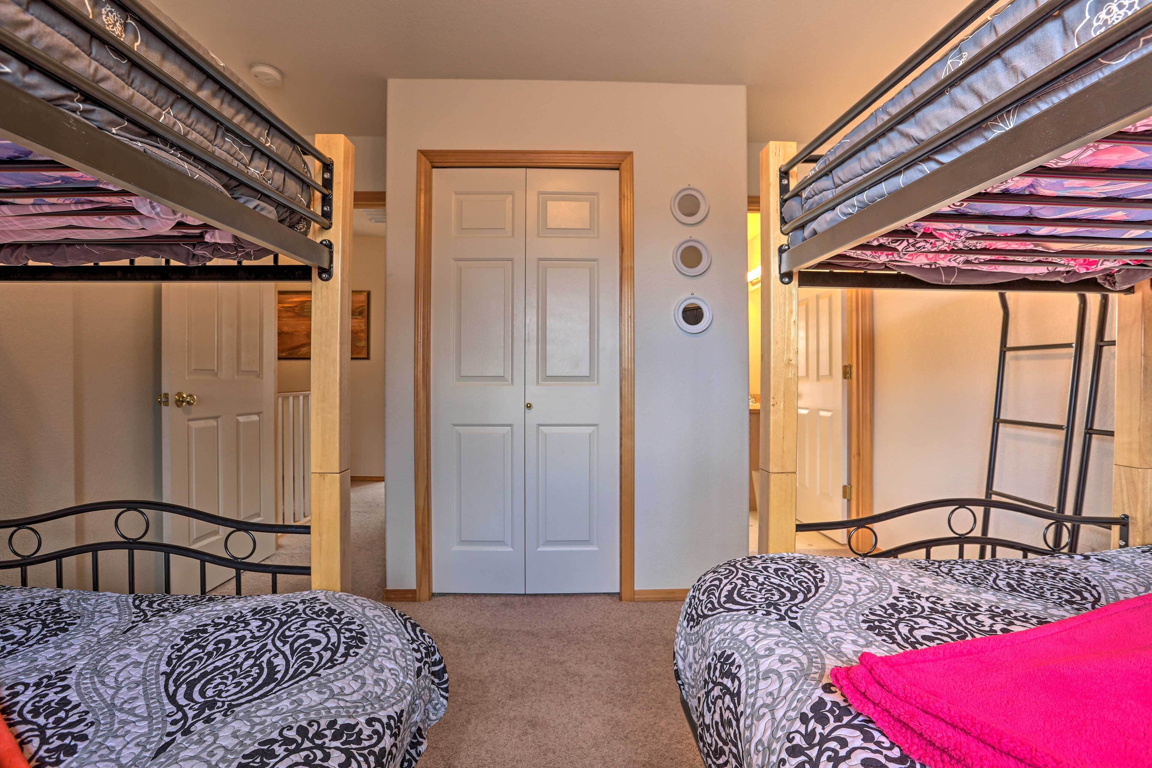 Ein Zimmer mit zwei Etagenbetten, einer weißen Tür und einem kleinen Wandregal mit drei runden Gegenständen.