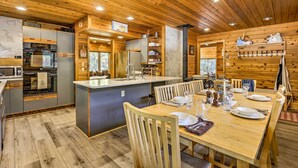 Une cuisine moderne avec des meubles en bois, un îlot central et un coin repas comprenant des chaises et une table en bois, le tout disposé pour accueillir quatre personnes.