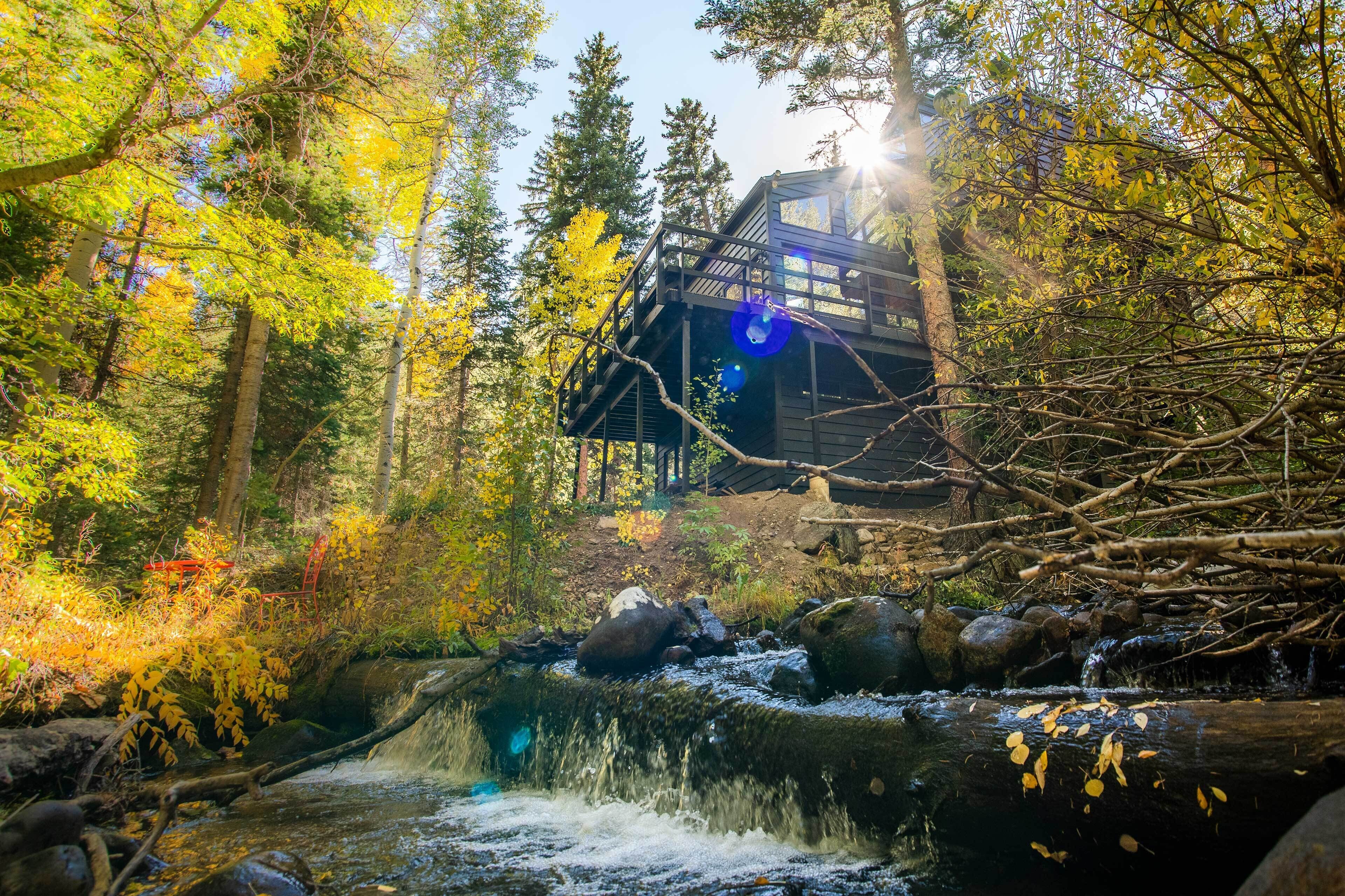 A cabin in a forest with a stream and a waterfall.