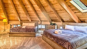 A wooden ceiling with a skylight, two beds with dark bedding, a nightstand, and a lamp. - 'zen Forest Mountain Retreat' Tahoe Home W/hot Tub (South Lake Tahoe)