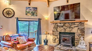 A cozy living room with a leather sofa, a stone fireplace, a large TV, and a clock on the wall. - 'zen Forest Mountain Retreat' Tahoe Home W/hot Tub (South Lake Tahoe)