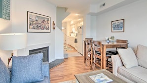 Een woonkamer met een open haard, een eethoek met houten meubels, en een keuken op de achtergrond.