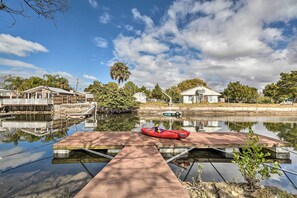 A calm water body with a dock, a red kayak, and houses in the background. - Serene Hudson Home on Canal w/ Direct Gulf Access (Hudson)