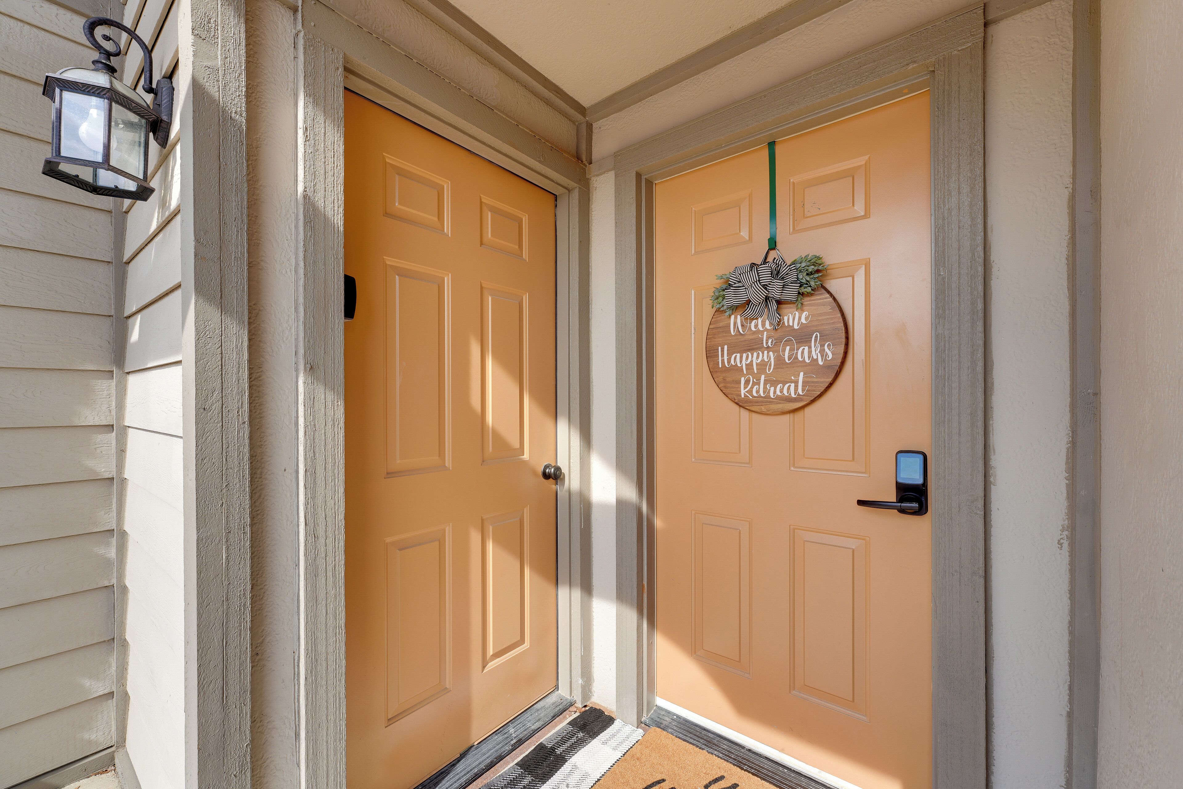 A front door with a doormat that reads "Welcome to Happy Oaks Retreat."