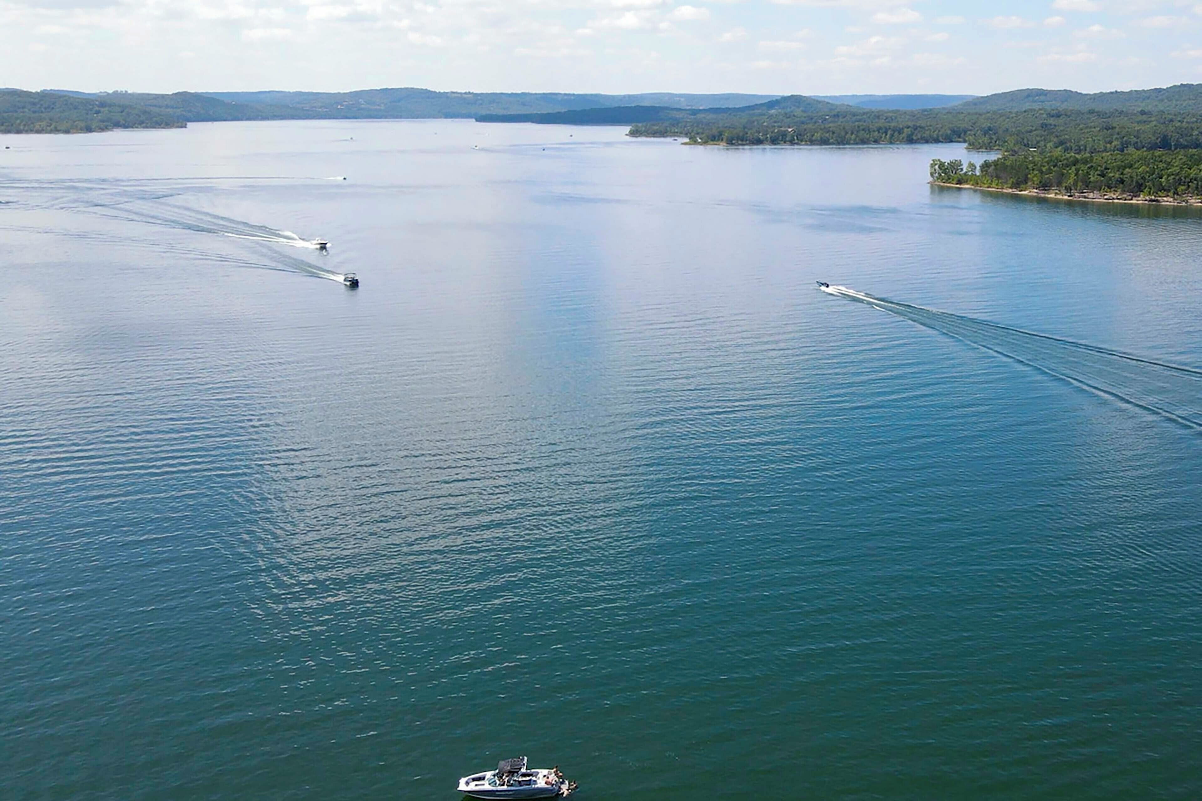 A large body of water with several boats creating wake patterns.