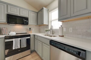 A modern kitchen with grey cabinets, a black microwave, a white toaster, and a dishwasher.