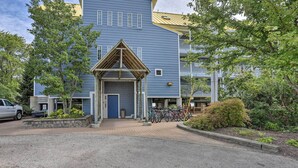 En bygning med blå facade, en trækonstruktion til indgang og et parkeringsområde med cykler.