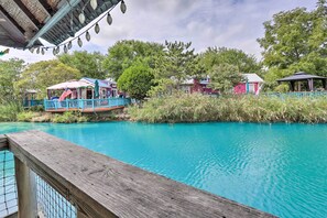 A wooden deck overlooking a clear blue pool with a boat docked on the left. - Middle Bass Condo w/ Balcony, Lake Erie Views (Put-in-Bay)