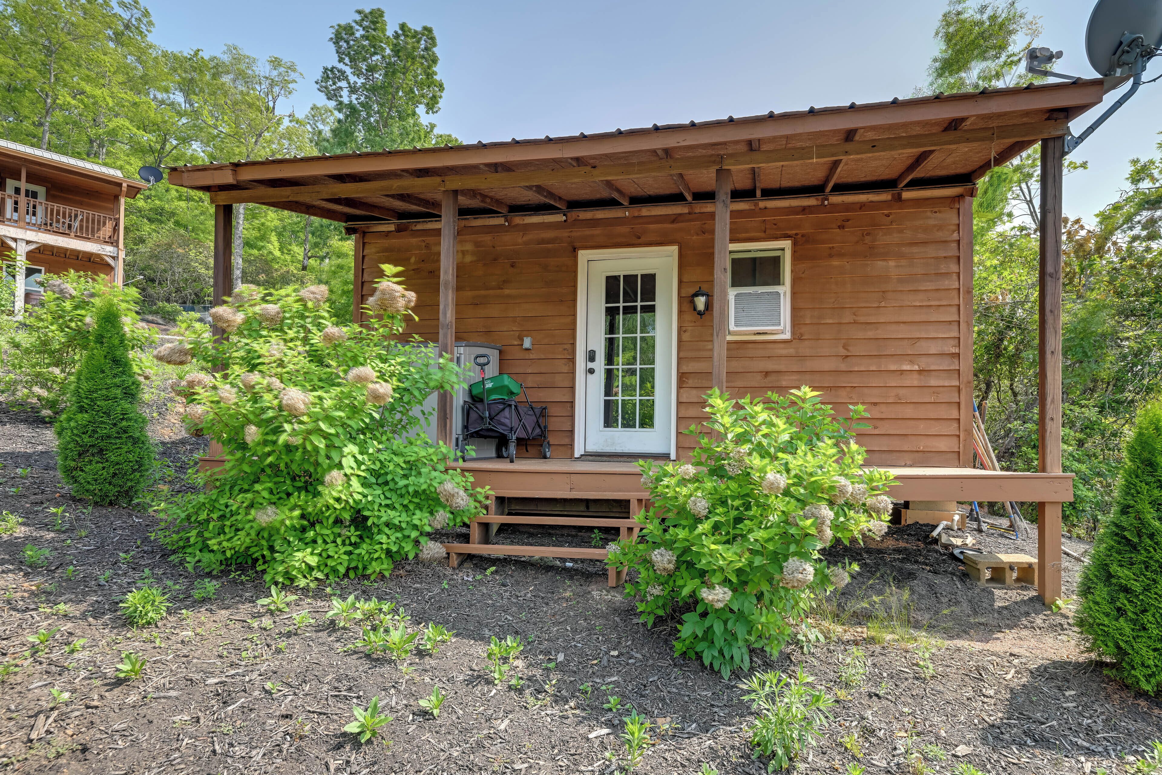 A wooden cabin with a porch, a door, and a satellite dish.