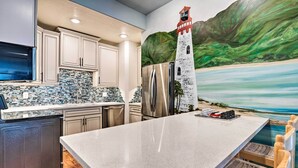 A kitchen with a large island, stainless steel appliances, and a mural of a lighthouse. - Mtn-view SLC Apt w/ Patio Near Downtown (Salt Lake City)